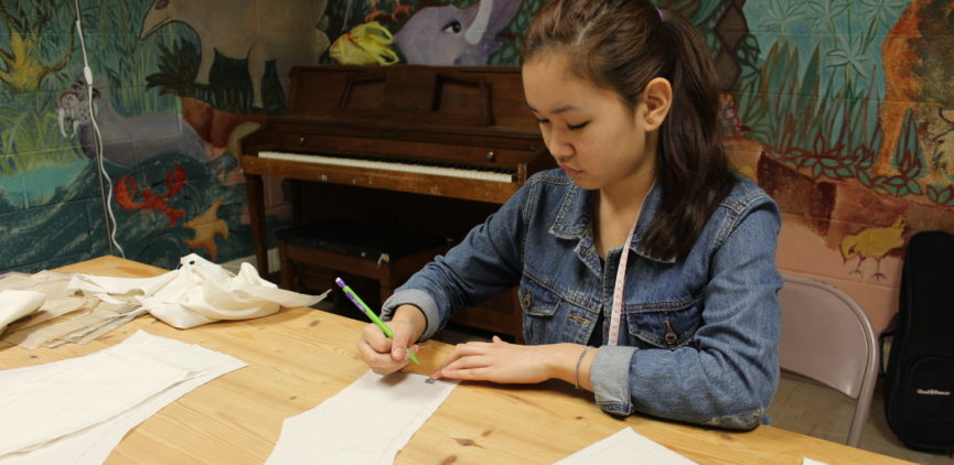 A teen who is interested in costume design, is marking out a pattern for a new design.